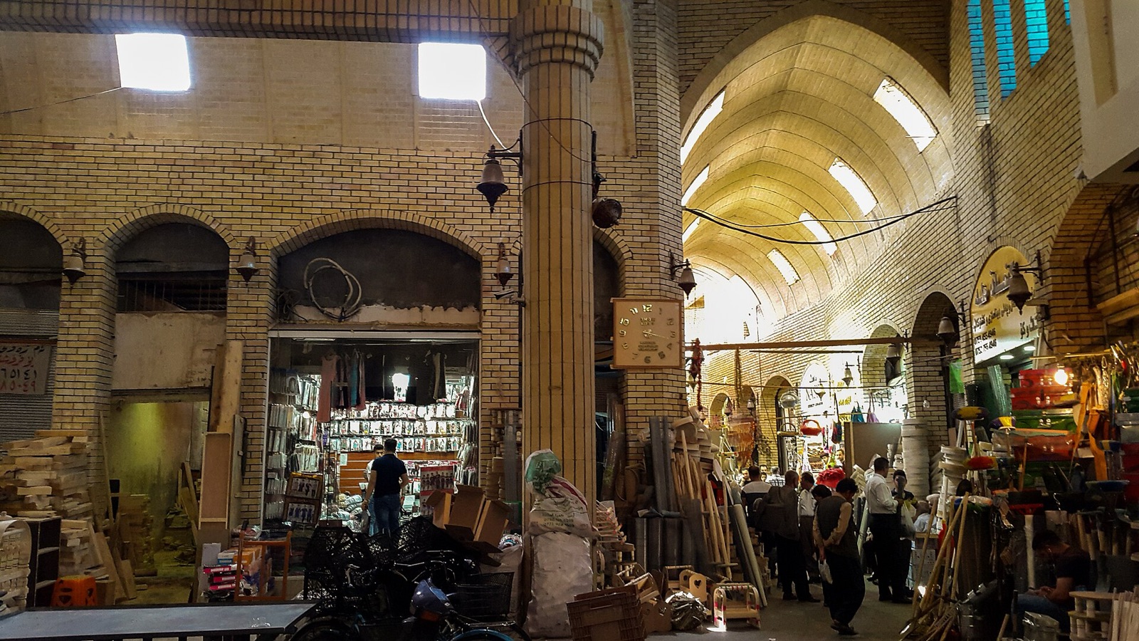 A vaulted market hall in Erbil, with shops, stacked goods and people walking through.
